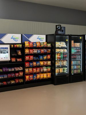 Row of glass-front vending machines and refrigerated coolers in a workplace break room